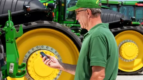 Worker standing next to tractor with phone in hand
